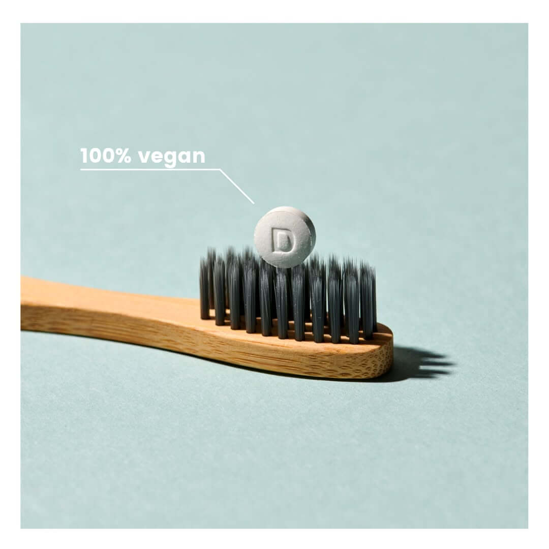Vegan ταμπλέτα οδοντόκρεμας Denttabs πάνω σε οδοντόβουρτσα με ένδειξη 100% vegan